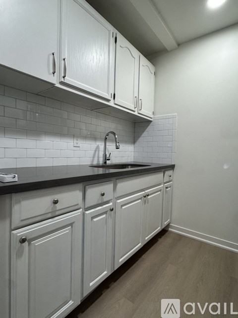 A kitchen with white cabinets and a black countertop.