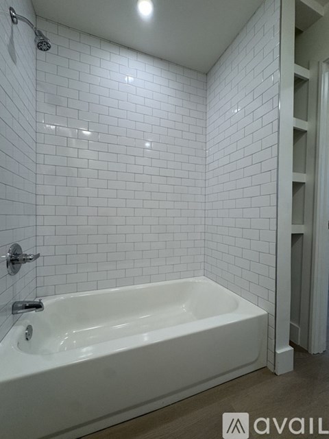 A white bathtub in a bathroom with white tiles.