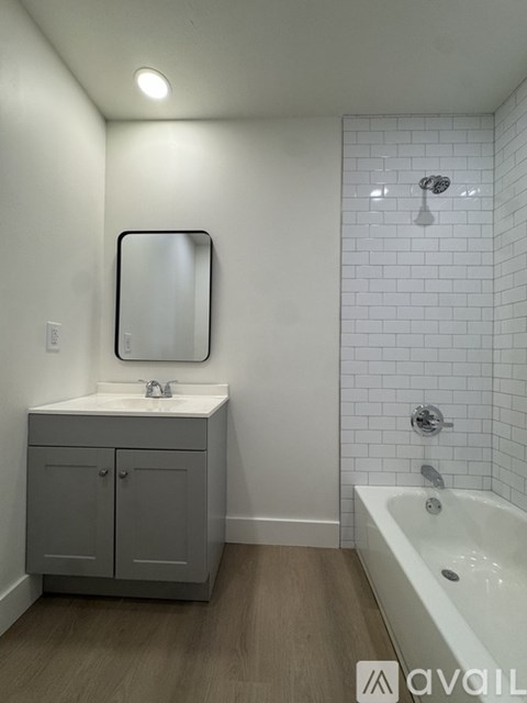 A bathroom with a white tub and a sink with a cabinet.
