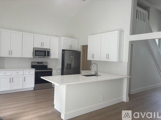 A kitchen with white cabinets and a black refrigerator.