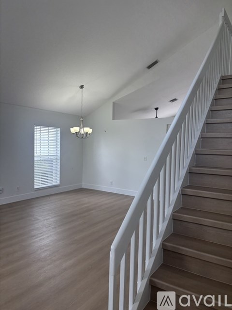 A room with a staircase and a chandelier.