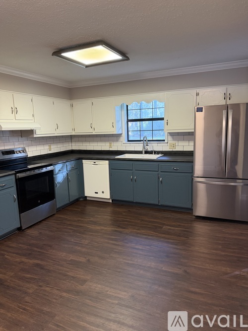 A kitchen with wooden floors and a stainless steel refrigerator.
