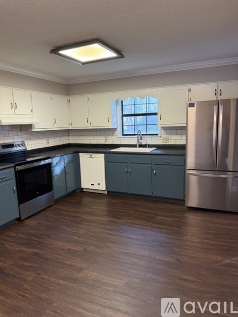 A kitchen with wooden floors and a stainless steel refrigerator.