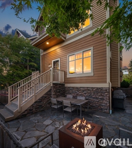 A house with a stone patio and a lit fire pit.