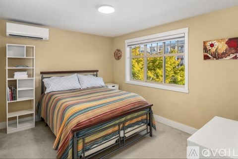 A bedroom with a large bed and a window showing trees outside.