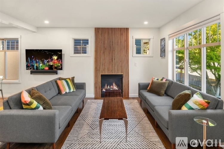 A living room with grey couches, a fireplace, and a television.