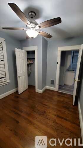 A room with a ceiling fan and wooden floors.