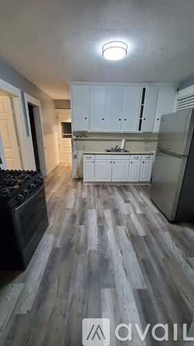 A kitchen with white cabinets and a wooden floor.