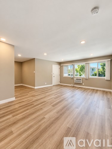 A spacious room with wooden flooring and a large window.