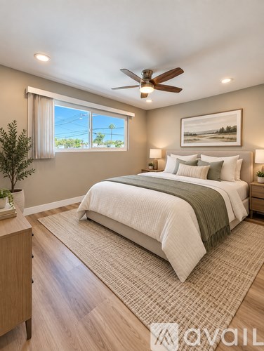 A bedroom with a bed, a ceiling fan, and a window with a view of the outdoors.