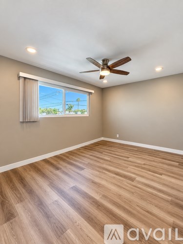 A room with a ceiling fan and wooden flooring.