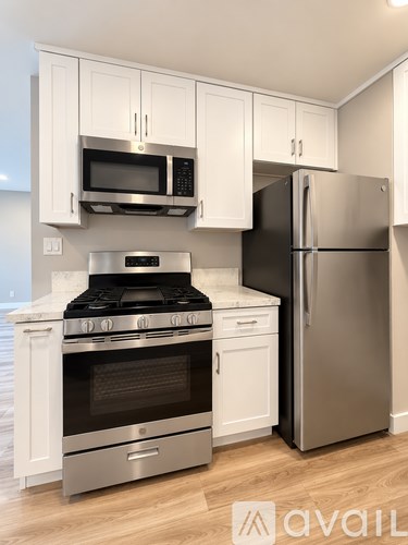 A kitchen with a stainless steel refrigerator and a stove with a black top.