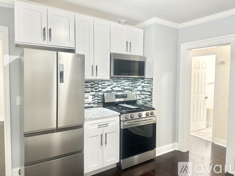 A kitchen with white cabinets and a stainless steel refrigerator.