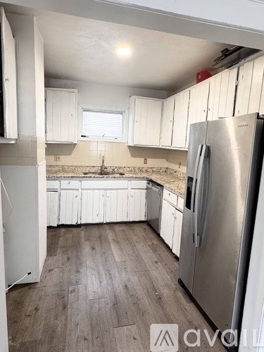 A kitchen with white cabinets and a stainless steel refrigerator.