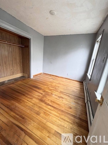 A room with wooden flooring and a white wall.