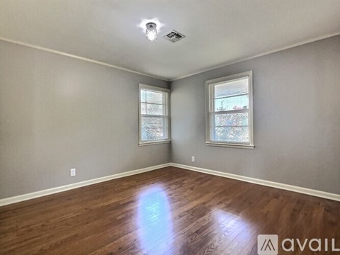 A room with wooden floors and two windows.