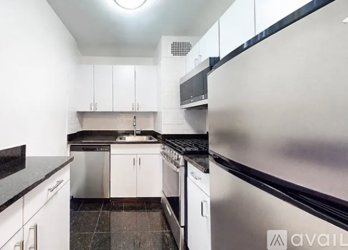 A kitchen with white cabinets and black countertops.