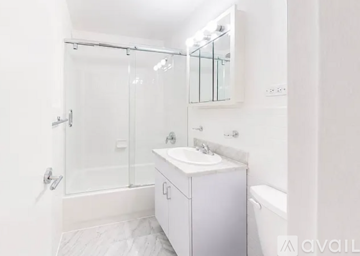 A white bathroom with a sink, mirror, and shower.