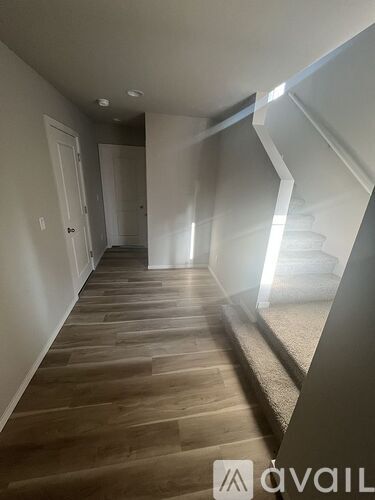 A hallway with wooden floors and white walls.