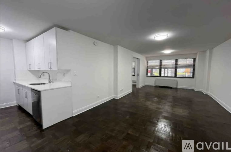 A spacious room with a kitchenette and wooden flooring.
