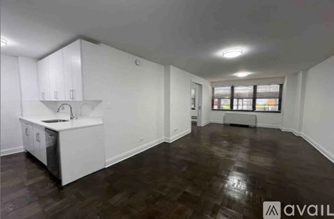 A spacious room with a kitchenette and wooden flooring.