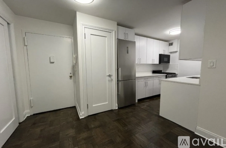 A kitchen with white cabinets and a wooden floor.
