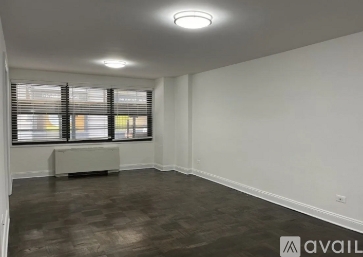 A room with wooden flooring and a window with blinds.