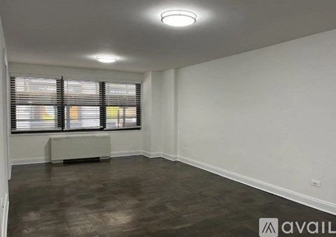 A room with wooden flooring and a window with blinds.