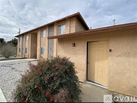 A beige stucco house with a white door and windows.