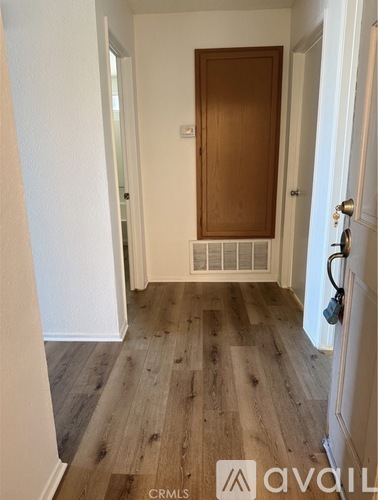 A hallway with a wooden door and tiled floor.
