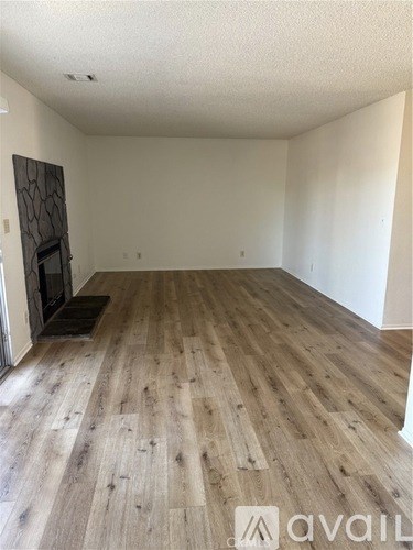 A room with wooden flooring and a fireplace.