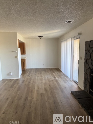 A spacious room with wooden flooring and a large window.