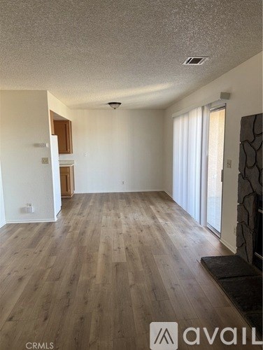 A spacious room with wooden flooring and a large window.