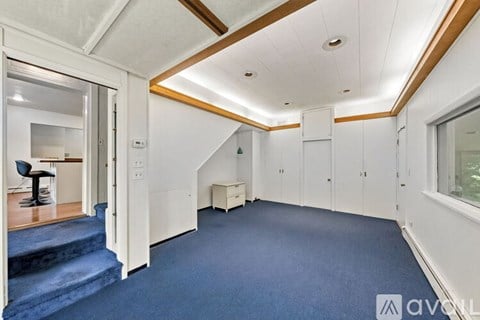 A spacious room with white walls and a staircase leading to another level.