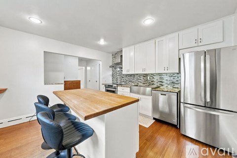 A kitchen with a wooden island and stainless steel appliances.