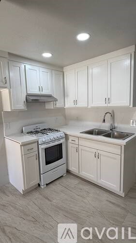 A kitchen with white cabinets and a white stove top oven.