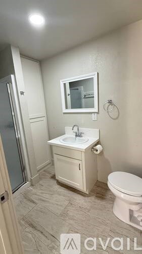 A small white bathroom with a toilet, sink, and shower.