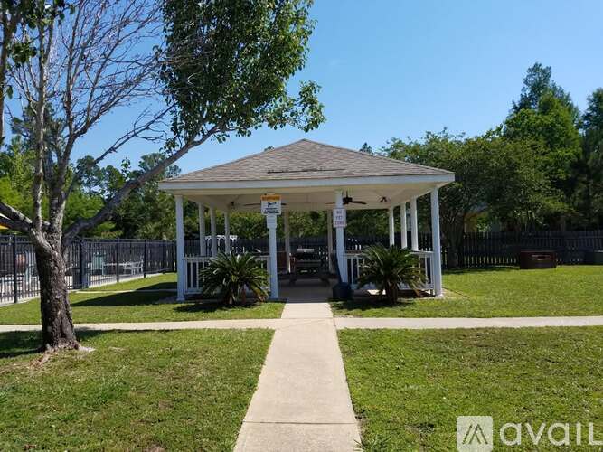 A gazebo is surrounded by a fence and trees.