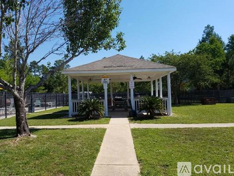 A gazebo is surrounded by a fence and trees.