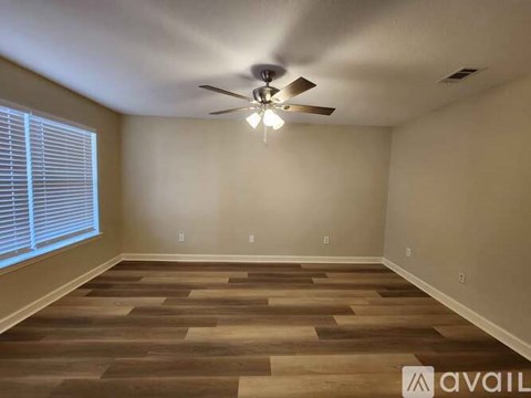 A room with a ceiling fan and wooden flooring.