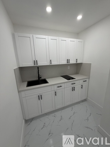 A kitchen with white cabinets and marble flooring.