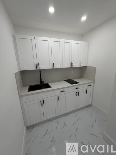 A kitchen with white cabinets and marble flooring.
