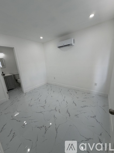 A room with a marble floor and an air conditioner mounted on the wall.