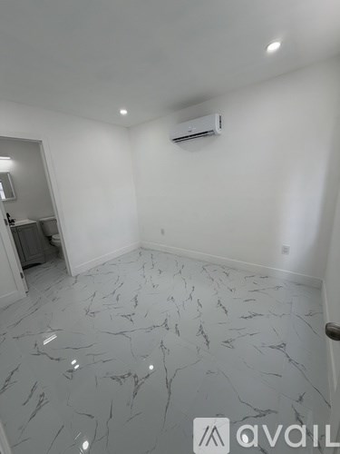 A room with a marble floor and an air conditioner mounted on the wall.