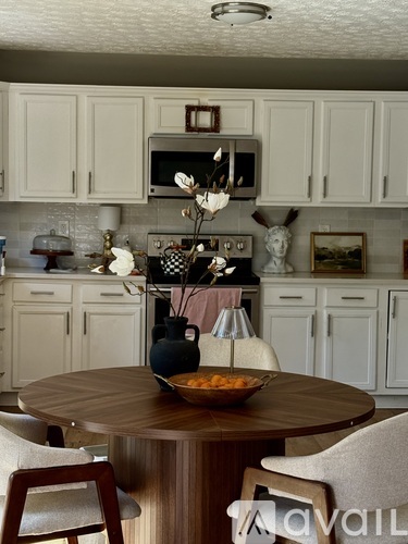 A kitchen with a table in the middle and chairs around it.