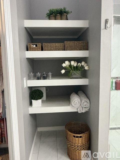 A white bathroom with a shelf and a basket.