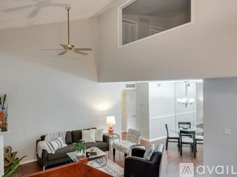 A living room with a grey couch, a wooden table, and a ceiling fan.