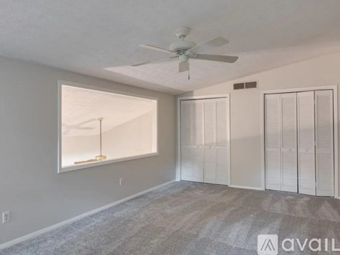 A room with a ceiling fan and a window with blinds.