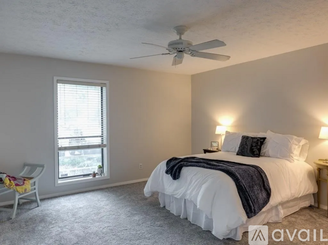 A bedroom with a large bed and a ceiling fan.