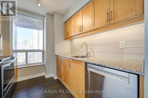 A kitchen with wooden cabinets and a stainless steel dishwasher.